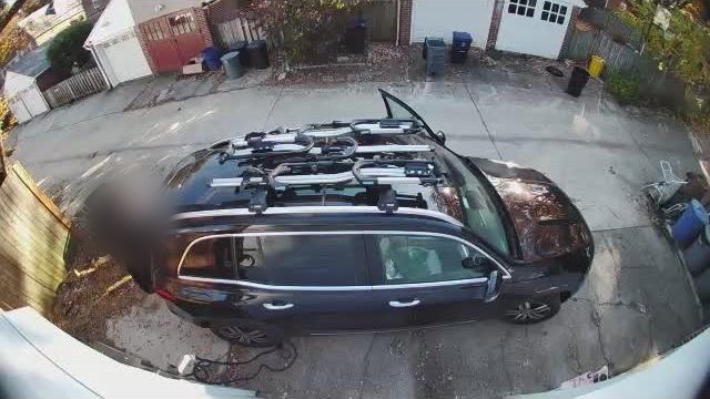 The alley in daylight: a dark SUV with bikes on the roof parked on the pad