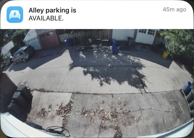 The notification on the lock screen: Alley parking is AVAILABLE, with the camera picture of the empty parking pad underneath